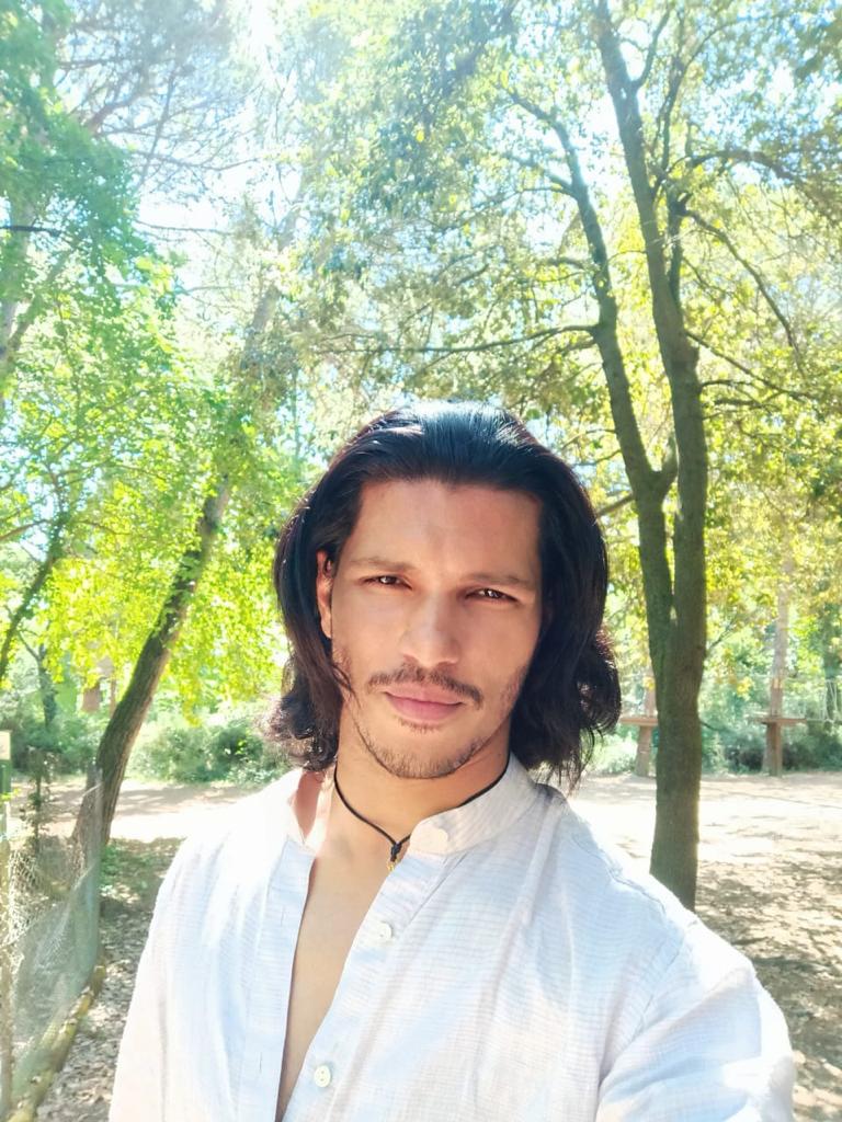 Suprotim Choudhury standing outdoors among sunlit trees